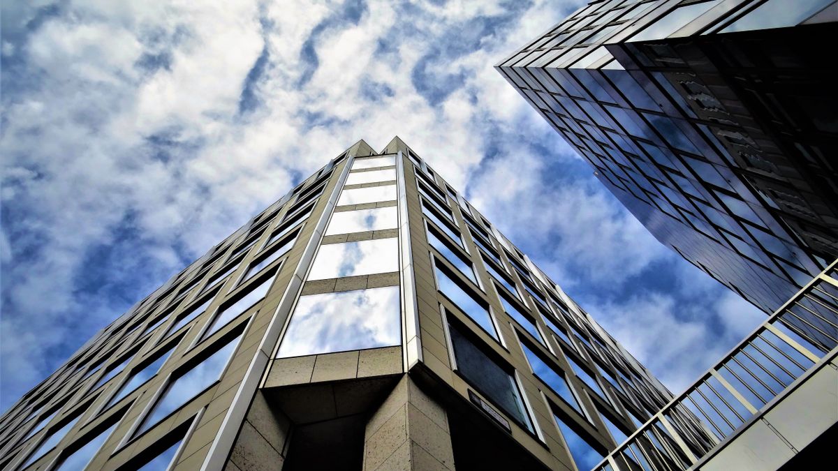 Low angle view of modern skyscraper with glass facade reflecting the sky.