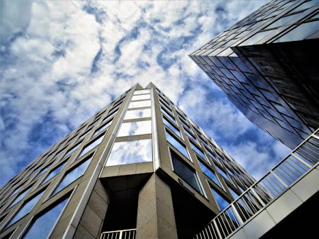 现代摩天大楼的玻璃立面反射着天空，呈现低角度视图