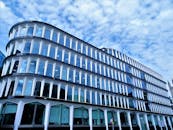 现代建筑的独特弧形设计和玻璃立面，映衬着部分多云的天空