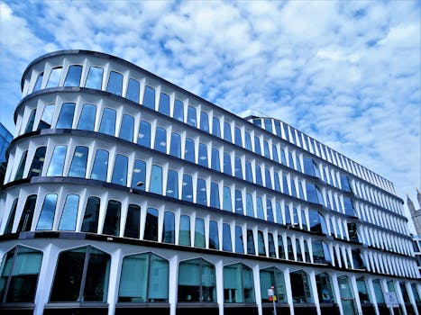 现代建筑的独特弧形设计和玻璃立面，映衬着部分多云的天空