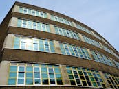 现代建筑立面的低角度视图中，玻璃窗映照着天空