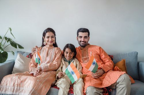 Free South Asian family celebrating with Indian flags indoors, smiling and bonding. Stock Photo
