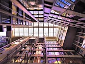 从低角度观看现代中庭，可见玻璃窗、钢梁及其倒影