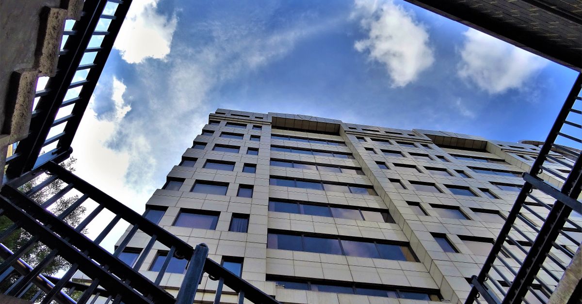 Dramatic low-angle shot of a modern skyscraper surrounded by blue skies and clouds.