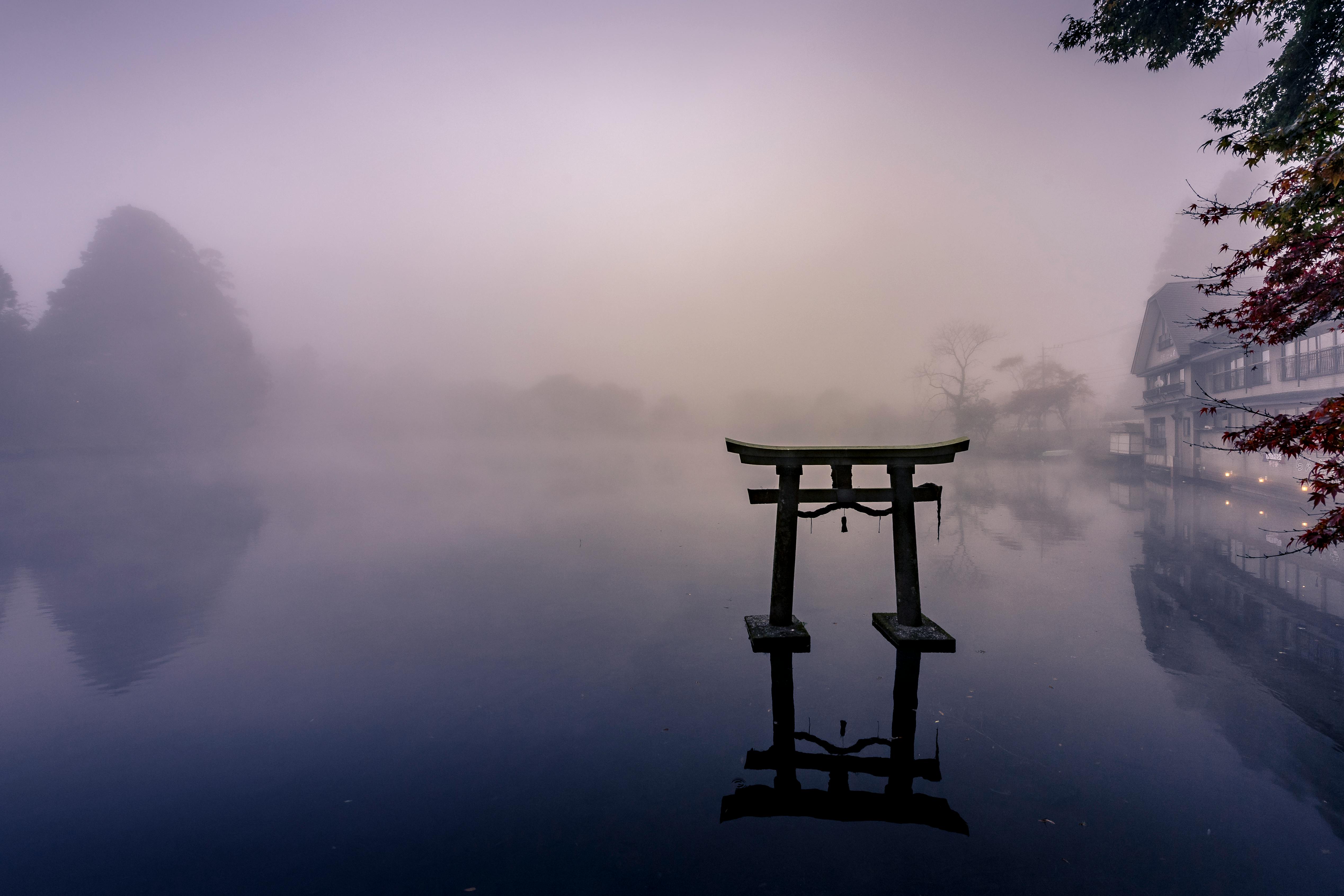 Misty morning at Lake Kinrin with a torii gate reflecting in the still waters, Yufu, Japan.