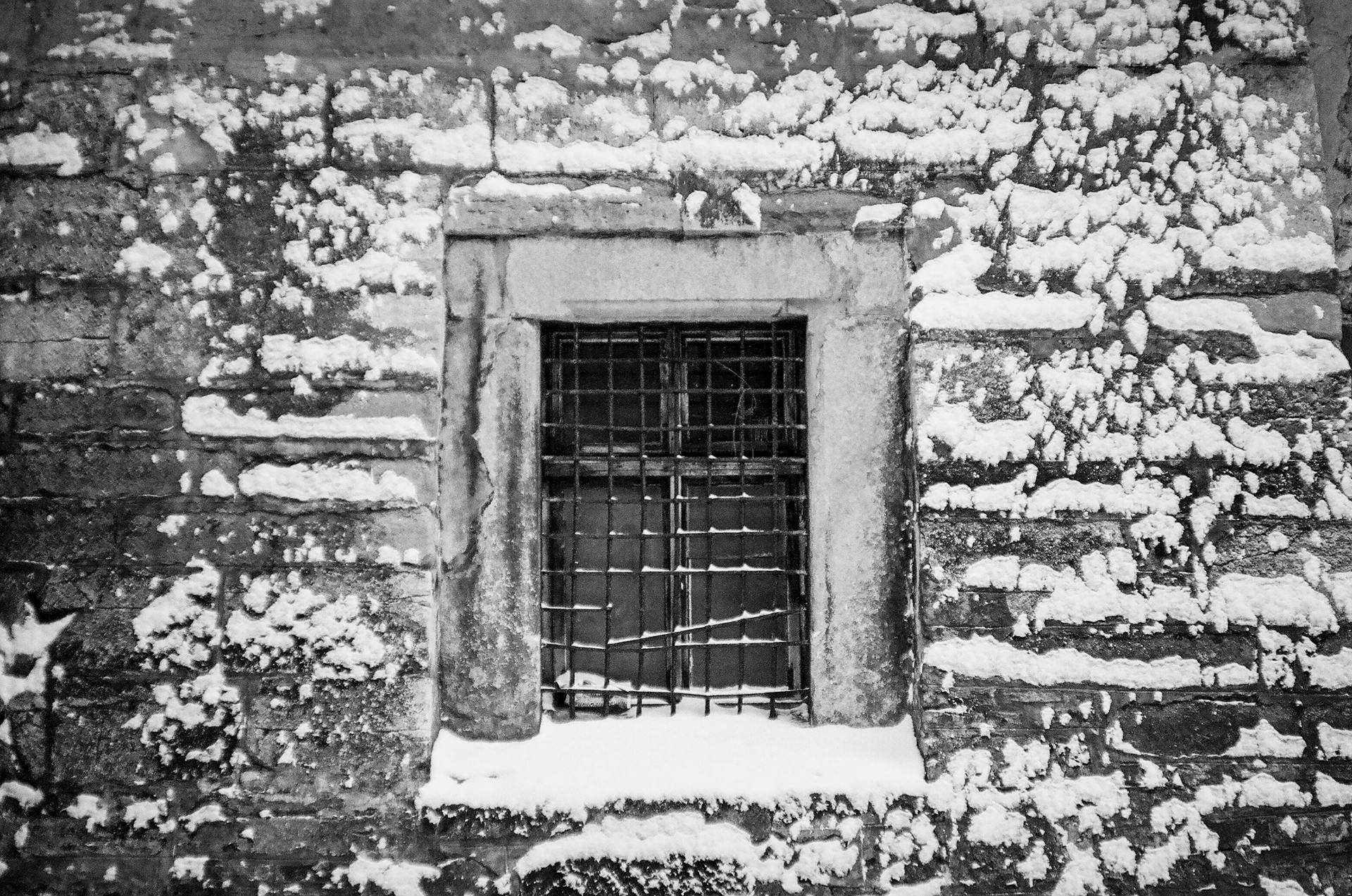 Black and white image of a barred window on a snow-covered building in Lviv, Ukraine.