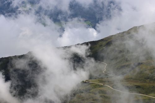 Free Misty mountain scene with a winding trail and clouds in the Alps. Stock Photo