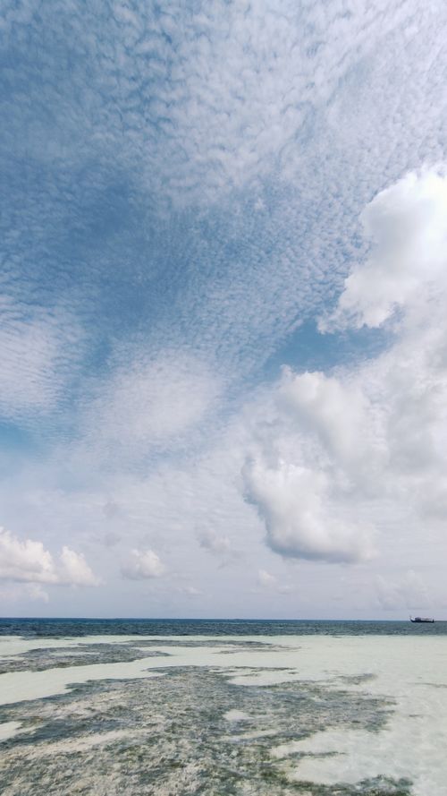 Free Tranquil beach scene at Dhangethi, Maldives with an expansive cloudy sky and calm sea. Stock Photo