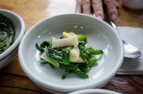 Free Close-up of a fresh leek and greens side dish served in a white saucer, garnished with sesame seeds. Stock Photo