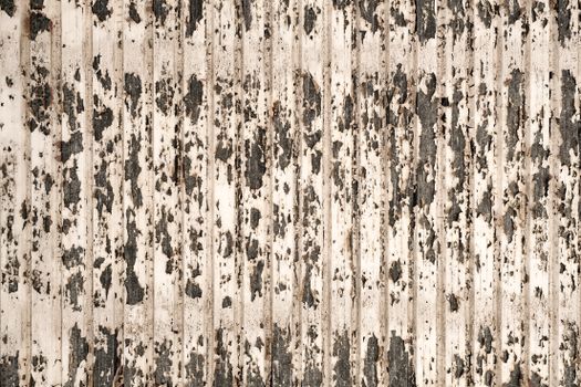 A close-up shot of a wooden wall with peeling paint creating a rugged texture.