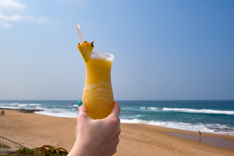 A Person Holding A Pineapple Cocktail