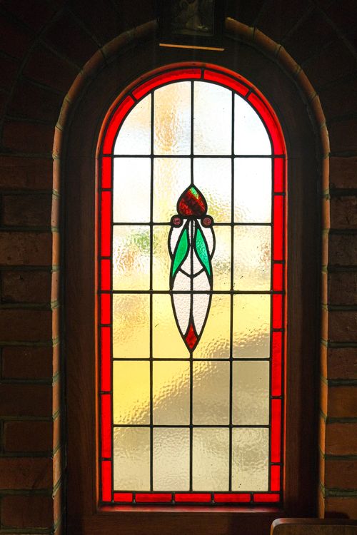 Free A beautiful stained glass window in a church with vibrant red and green hues. Stock Photo