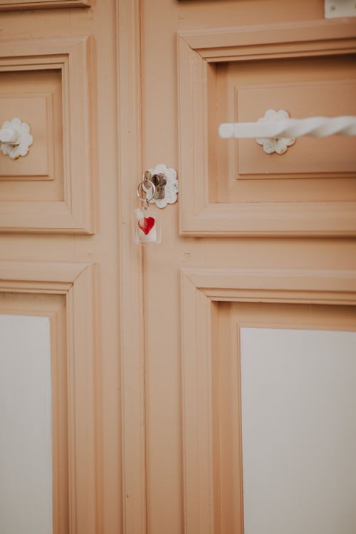 Free Close-up of a beige wooden door featuring a heart-shaped keychain. Stylish and captivating. Stock Photo