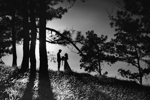 Grayscale Photo of Couple Standing on the Forest