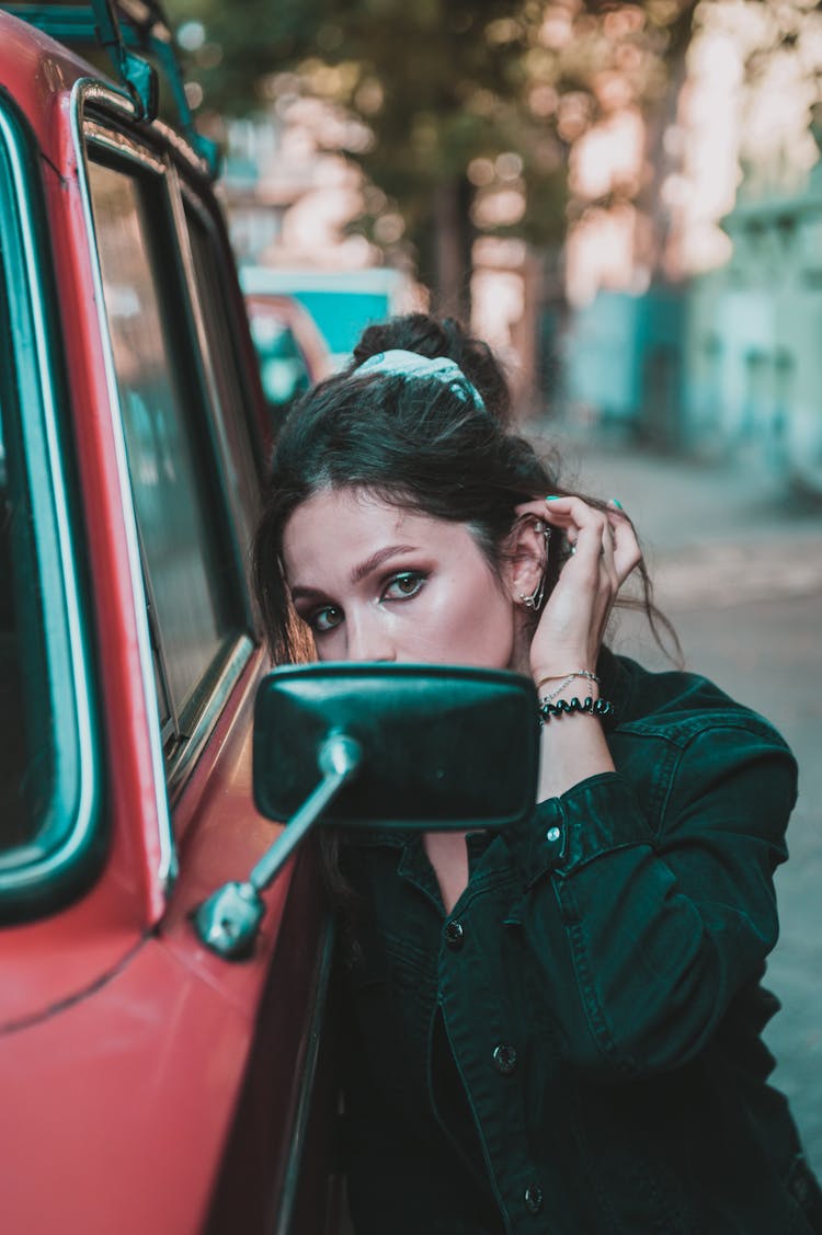 Woman In Black Jacket Looking At The Side Mirror Of A Car 