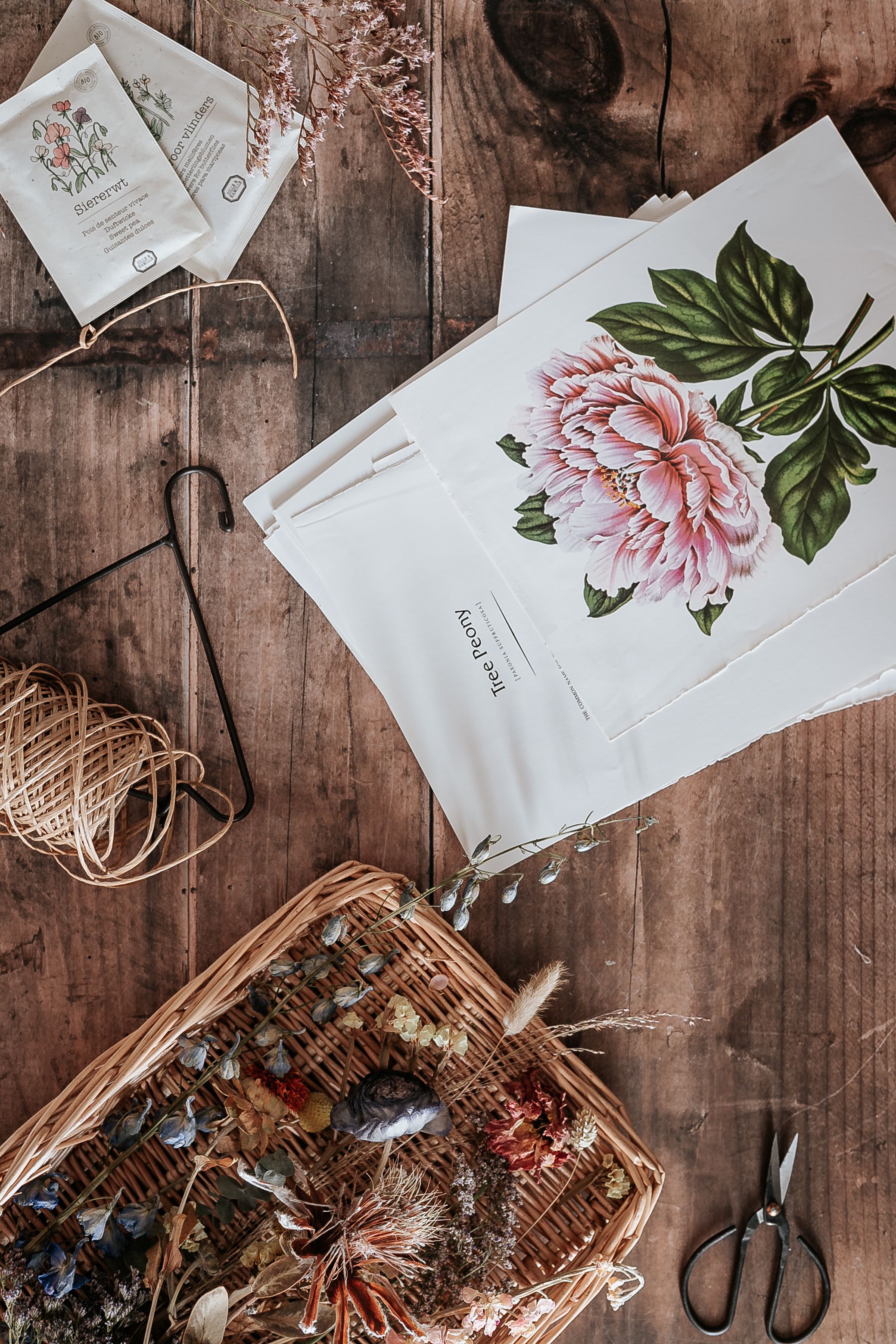 Top view of floral artwork alongside natural crafting materials on a rustic wooden table.