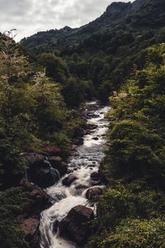 A scenic mountain river winds through lush green forest, offering a serene nature view.