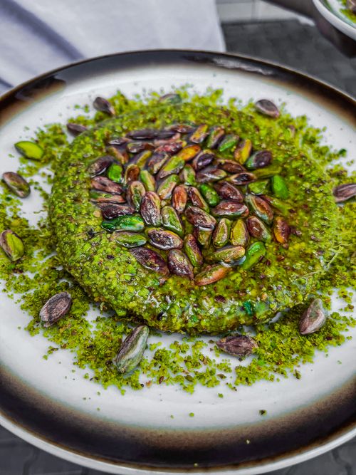 Free Close-up of a pistachio dessert with vibrant green nuts and crumbs on a plate. Stock Photo