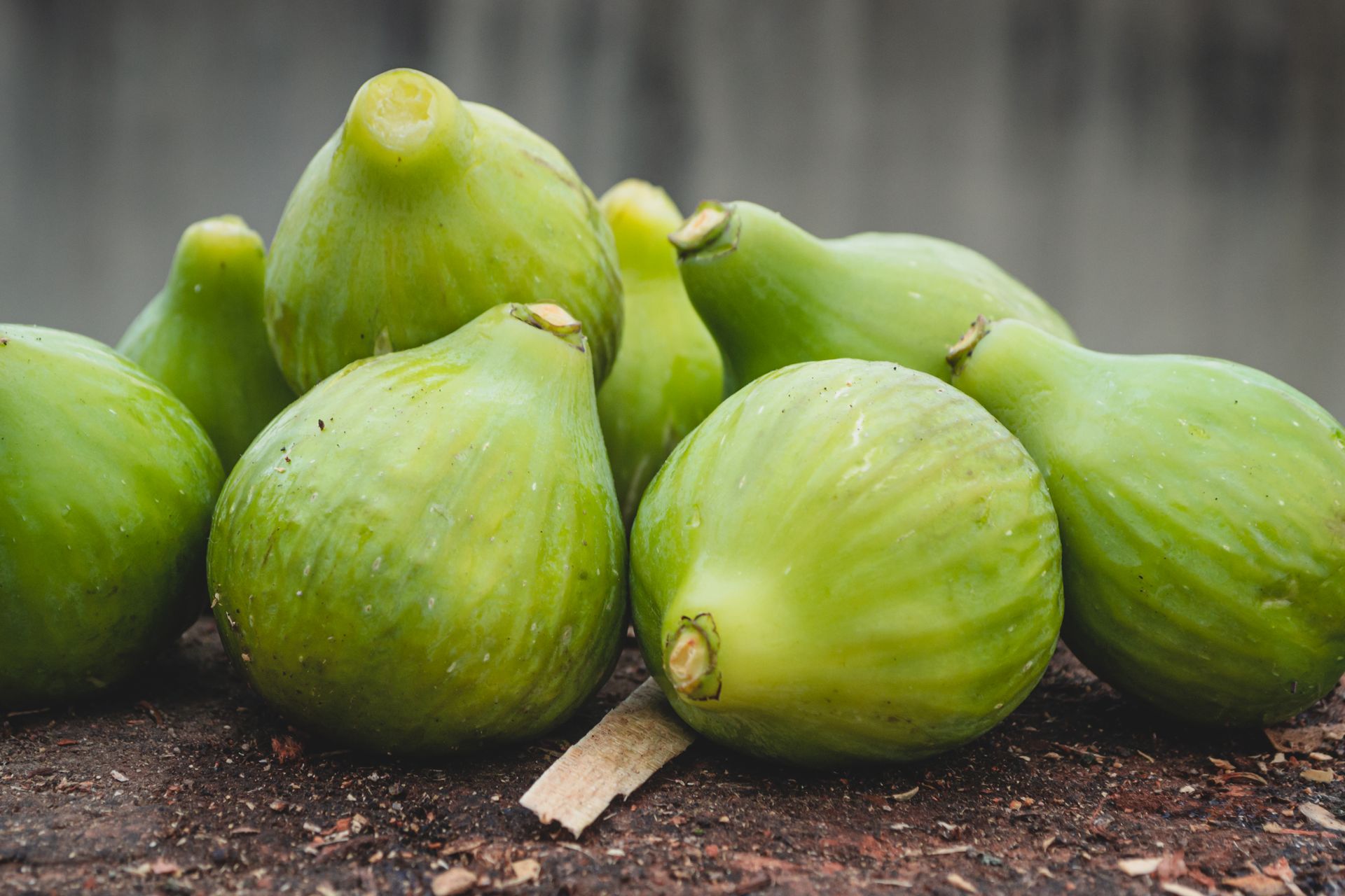 Close-up of fresh green figs on a rustic surface, showcasing a blurred background.