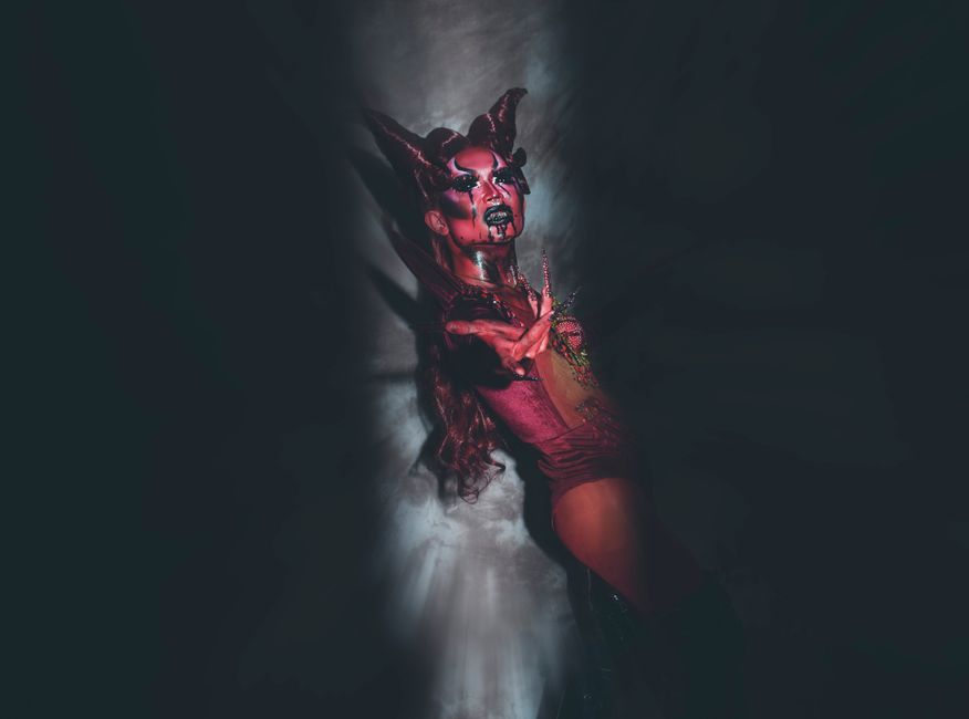 A striking studio image of a performer in fantasy costume with dramatic makeup and horns.