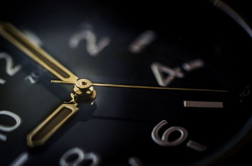 Macro of a black watch dial with gilt hands, photo by ClickerHappy on Pexels