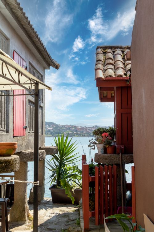 Free Idyllic coastal view between traditional buildings, revealing serene sea and sky. Stock Photo