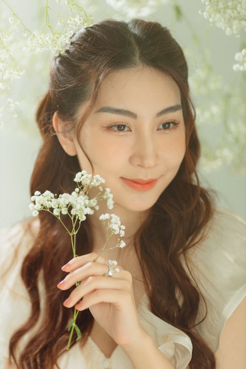 Free A close-up portrait of a smiling woman holding delicate white flowers. Stock Photo