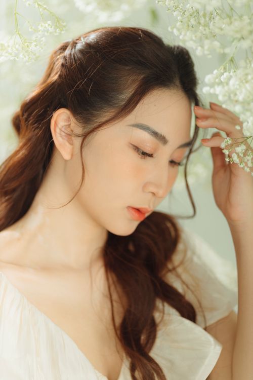Free Portrait of a young woman with delicate features in a soft floral setting, exuding elegance. Stock Photo