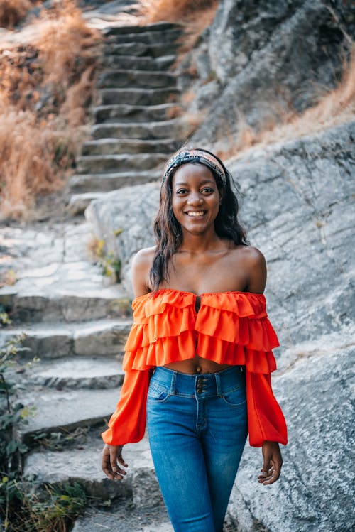 Free Woman in Orange Off Shoulder Top Standing on Concrete Stairs Stock Photo