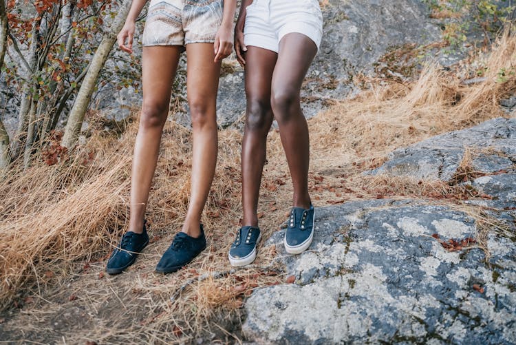 Women In Shorts Wearing Black Shoes Standing On Rocks