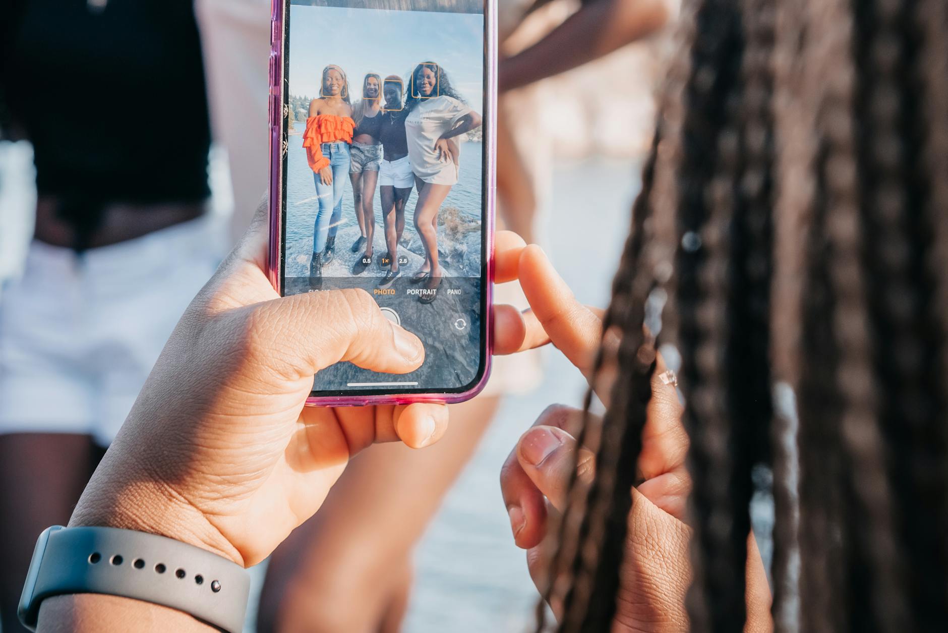 Group of friends taking a photo with a smartphone during a sunny day outdoors