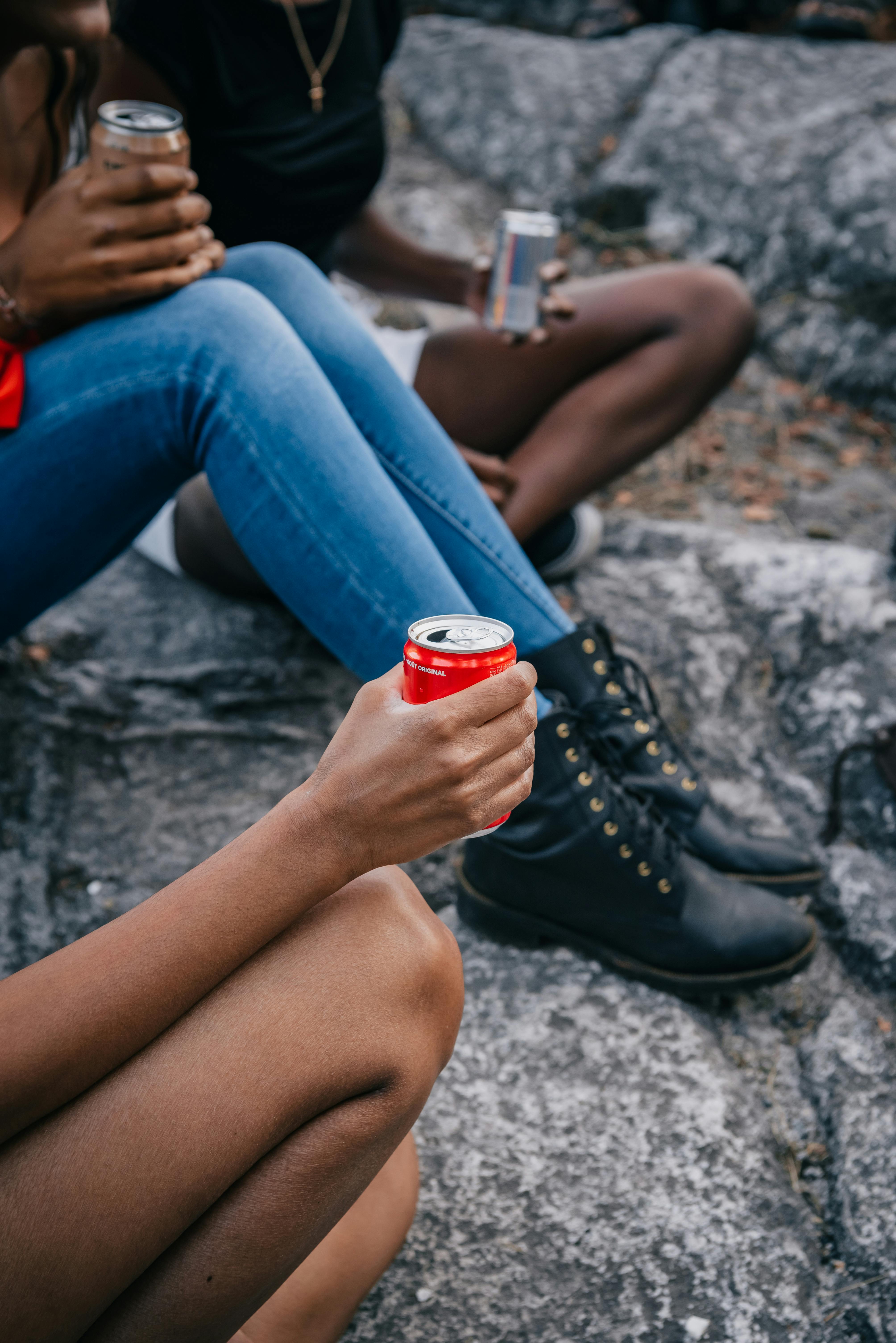 person in blue denim jeans holding red can