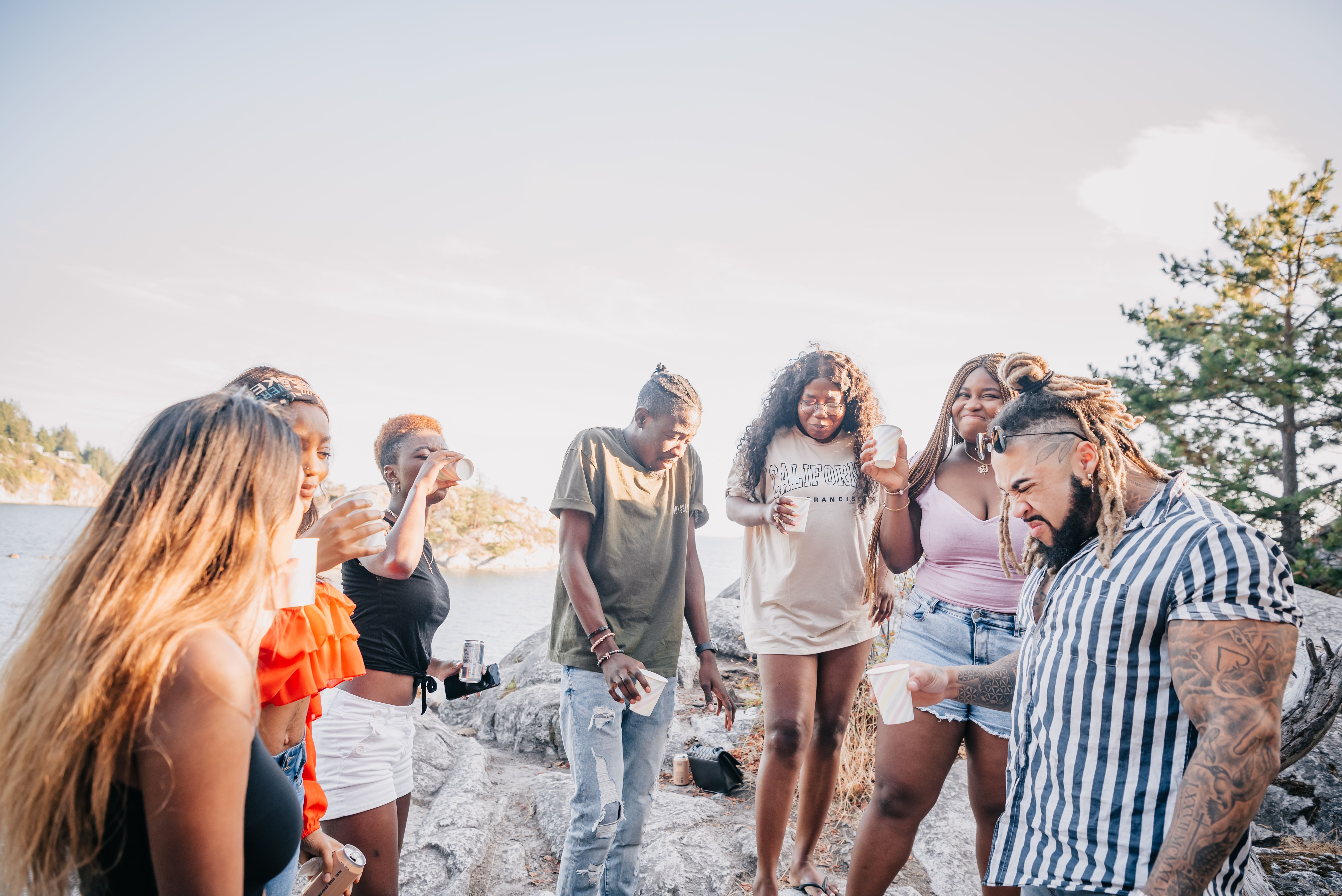 A lively group of friends having fun, drinks, and laughs at a sunny beach party.