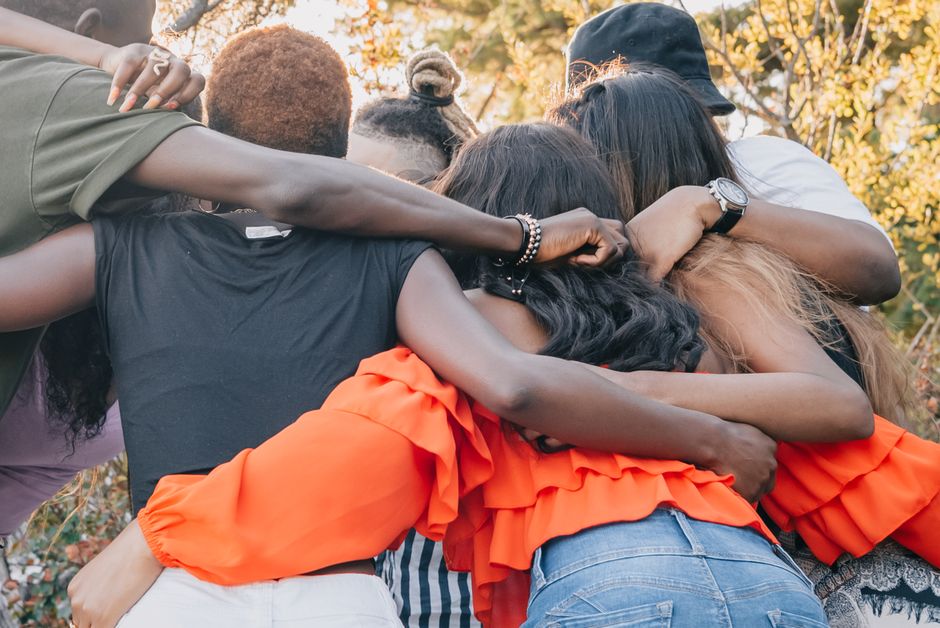 A diverse group of friends shares a warm embrace outdoors, symbolizing unity and joy.