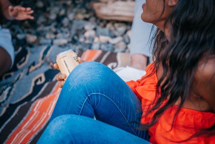 Woman In Orange Top Holding A Can