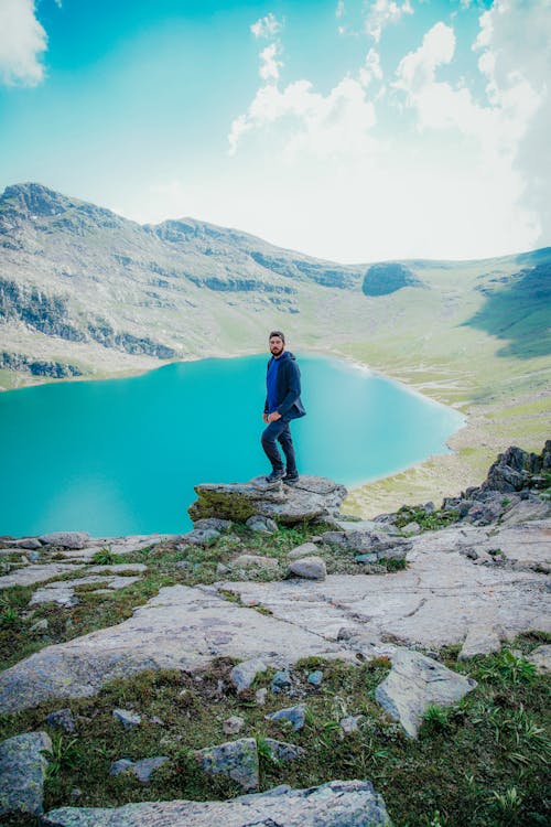 Man Posing on Rocks with Lake in Background