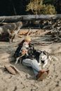 Man and Woman Sitting on Brown Log Beside White and Black Siberian Husky