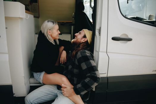 Happy couple bonding and laughing while embracing van life lifestyle outdoors.