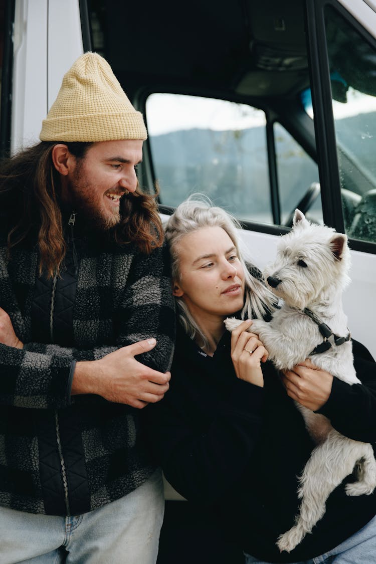 Woman Carrying A Dog Beside A Man