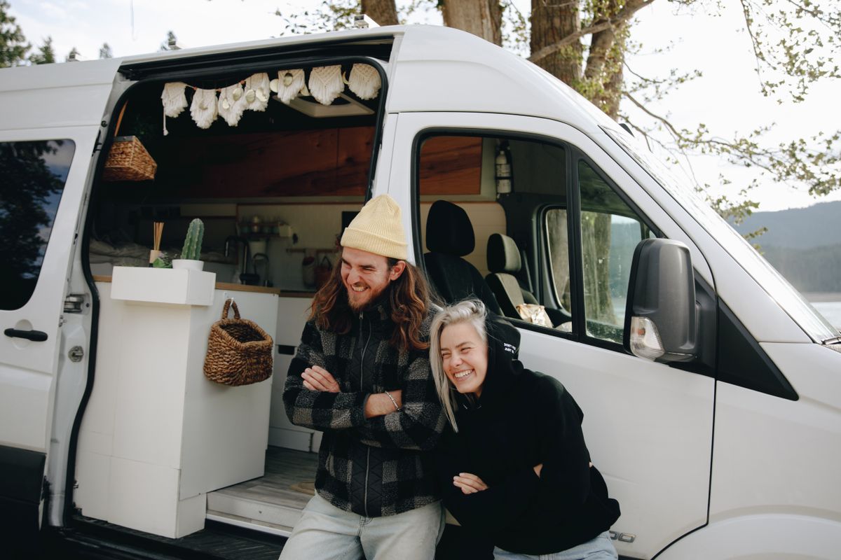 Couple leaning against their campervan and laughing