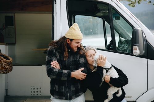 Free A couple and their dog enjoying a moment by their campervan, outdoors in nature. Stock Photo