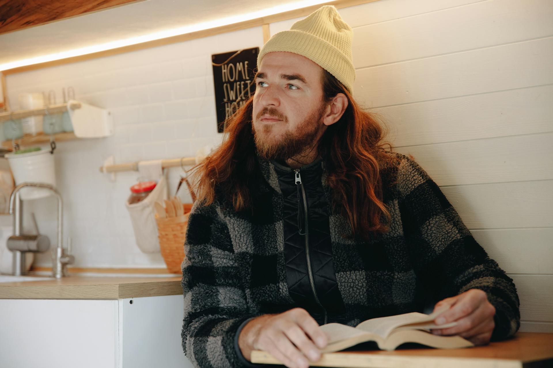 A man sits comfortably in a camper van interior, reading a book and relaxing.