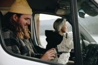 Man and woman enjoy a scenic road trip with their dog in a van.
