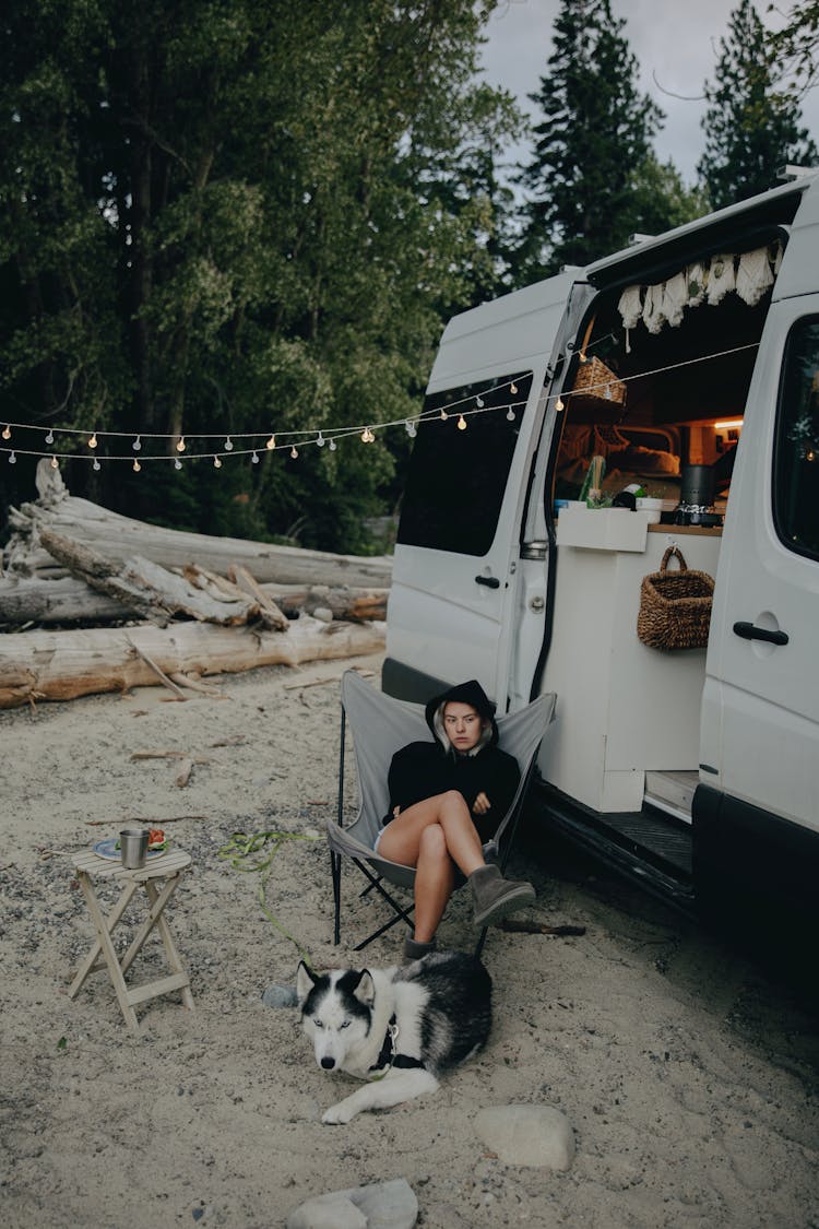 A Woman Camping With A Dog Outdoors