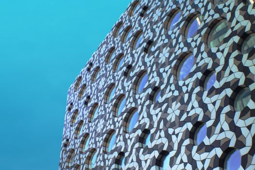 Close-up of a building's geometric facade with circular windows and vibrant patterns against a blue sky.