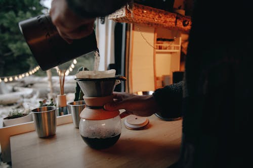 Close-up of Person Pouring Hot Water into a Coffee Pot in a Campervan 