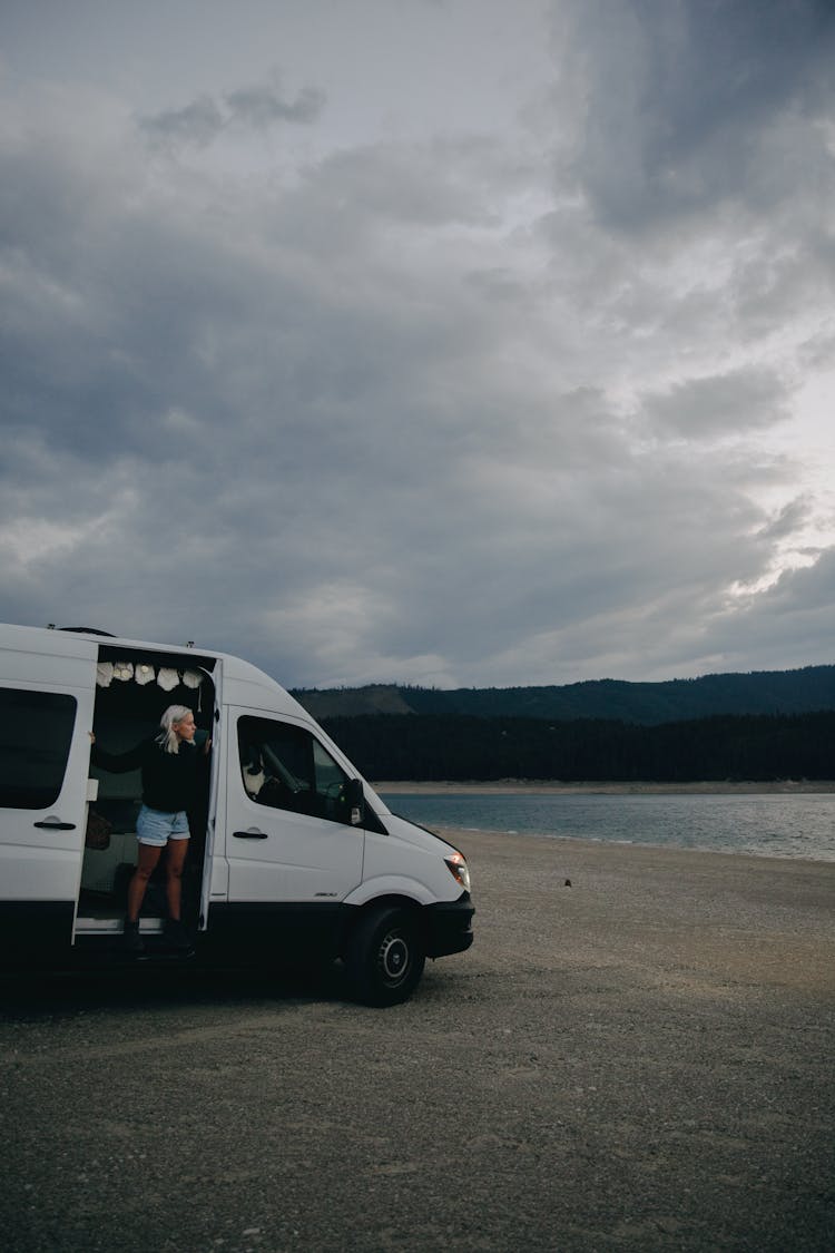 Woman Standing In A Campervan While Looking At The Beach