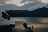 A Man Sitting on a Camping Chair Near a Body of Water