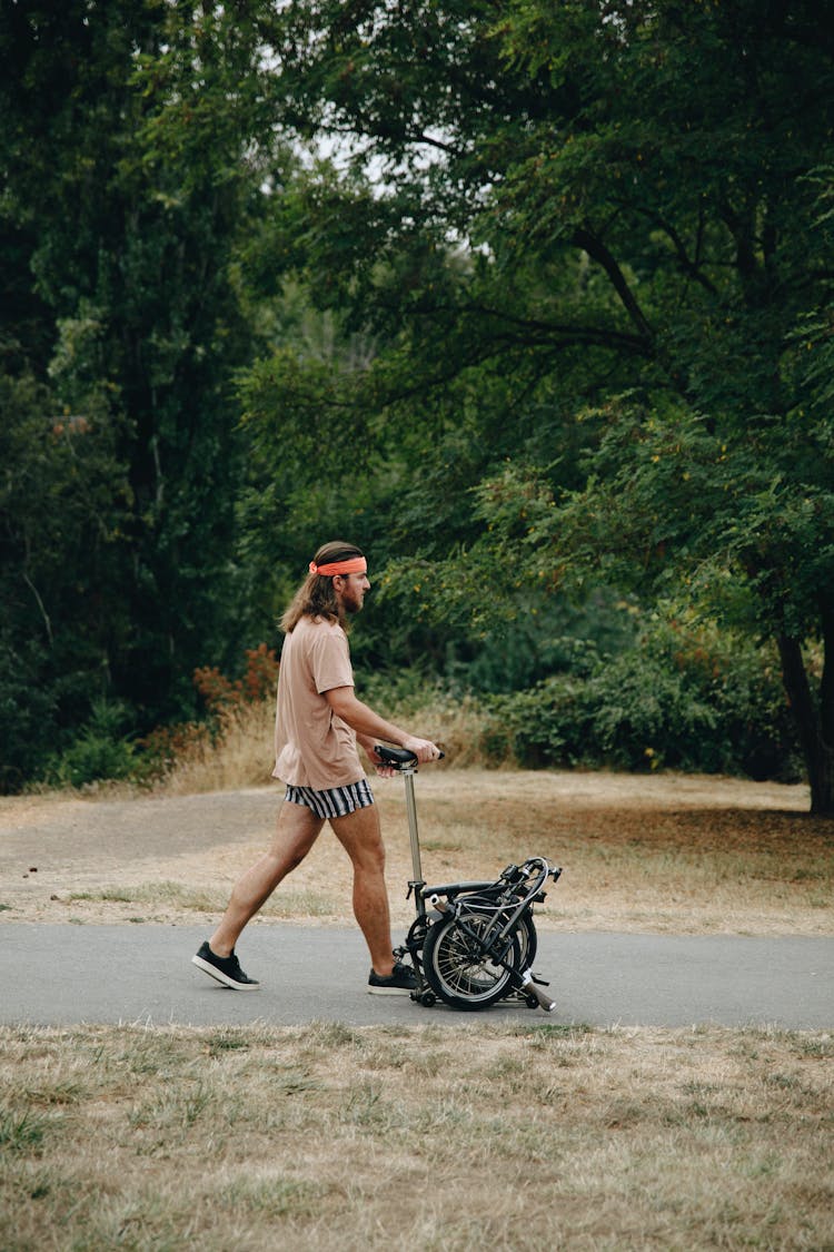 Man Pushing A Folding Bicycle