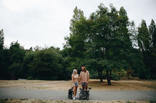 Free A couple enjoys a day outdoors with foldable bicycles, set against lush greenery. Stock Photo